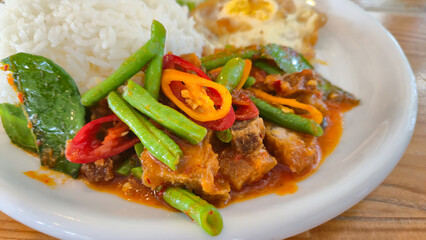 Thai Stir-Fried Pork Belly Crisp with Red Curry and Salted Egg served with rice on white plate