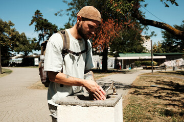 Young man washing his hands at a public park fountain during summer. Concept of hygiene, refreshment, and outdoor lifestyle