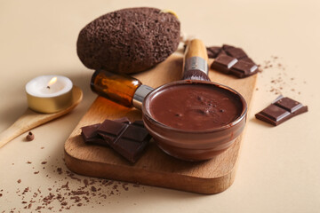 Beautiful spa composition with wooden tray and bowl of melted chocolate on beige background, closeup