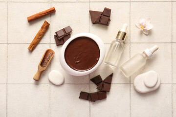 Beautiful spa composition with bowl of melted chocolate and bottles of cosmetic products on tile background