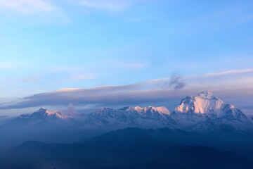 A scenic view of the snow-capped Himalayas mountain range with blue skies. Taken along a trekking road, on the way to Annapurna Base Camp in Nepal