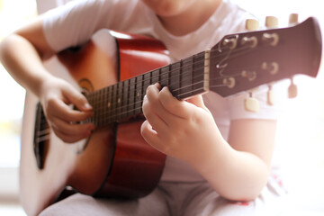 Child's hands on guitar strings.
