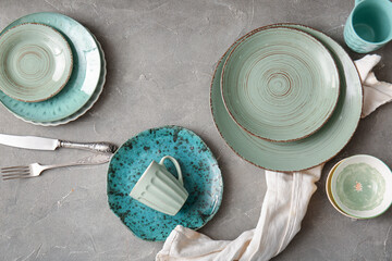 Set of clean dishes, cutlery and napkin on grunge background