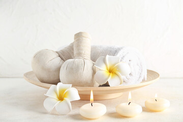 Beautiful spa composition with candles, herbal bags and flowers on light background