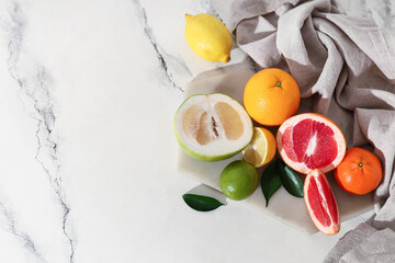 Napkin, tray and tasty citrus fruits on marble background