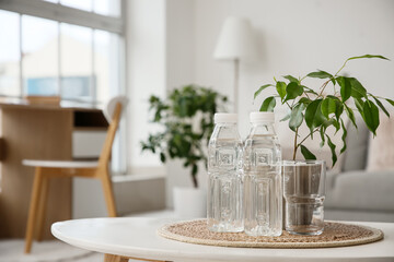 Bottles of water and glass on table in room, closeup