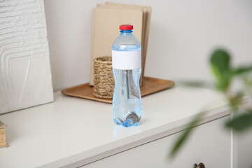 Bottle of water on chest of drawers in room, closeup
