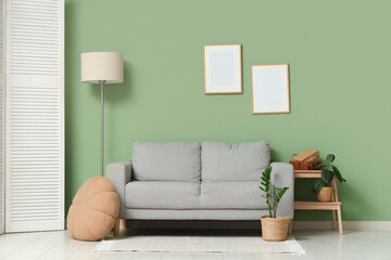 Interior of living room with floor lamp, folding screen and sofa near green wall