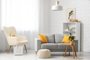 Sofa and pouf near white brick wall in interior of living room