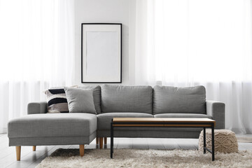 Comfortable sofa near window with white curtains in interior of living room