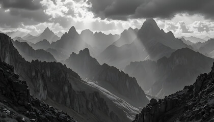 High contrast black and white craggy mountain ridges with piercing sunlight shafts