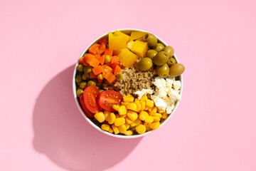 Healthy quinoa bowl with vegetables on pink background, closeup