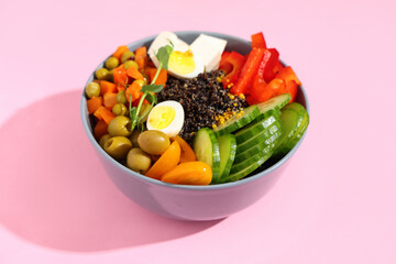 Healthy quinoa bowl with vegetables on pink background, closeup