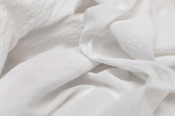 Close-up of a white crinkled cotton fabric, beautifully draped and softly lit, forming an abstract background