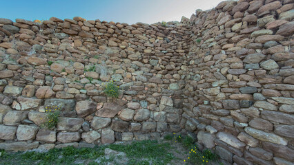 Archaeological remains of a Nuraghe stone structure in Sardinia, Italy, surrounded by wild...