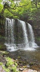 Beautiful natural waterfall surrounded by green forest, Wales UK 
