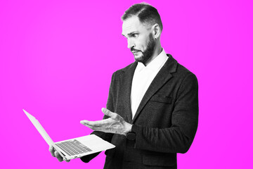A focused professional man stands against a vibrant colored backdrop, examining ideas on a laptop,...