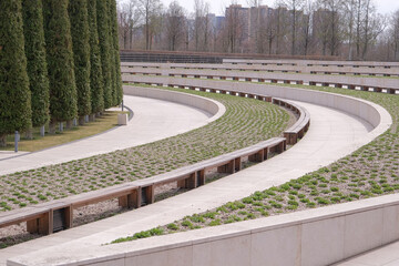 Obraz premium Walkway in Garden with curvy benches and tall trees