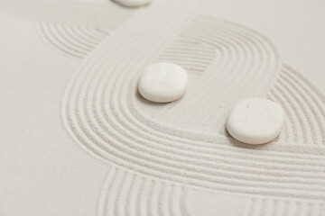 Spa stones on light sand as background, closeup. Zen concept
