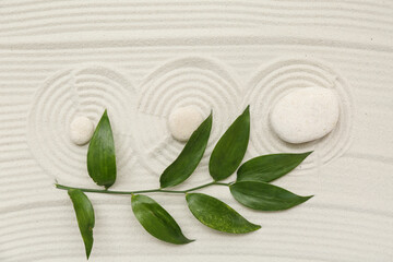 Composition with spa stones, green twig and lines on sand as background, closeup. Zen concept