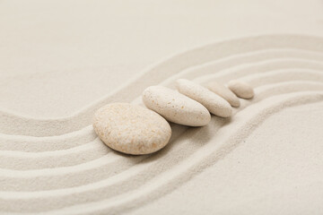 Composition with spa stones and lines on sand as background, closeup. Zen concept