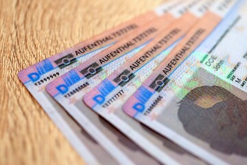 German Permanent resident specimen cards lies on wooden table close up. Aufenthaltstitel