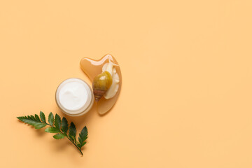 Giant Achatina snail, jar with cosmetic product and guasha tool on beige background