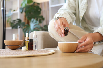 Young woman dropping essential oil into air humidifier at home, closeup