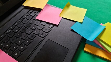 Colorful sticky notes scattered across a laptop keyboard and desk