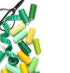 Many thread spools with scissors and measuring tape on white background