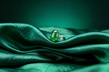 An exquisite jade ring with a large green oval gemstone is displayed on luxurious, deep emerald green silk fabric. This vibrant image conveys luxury, sophistication, and oriental elegance.