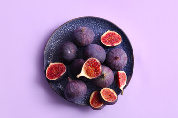 Plate with fresh ripe figs on lilac background
