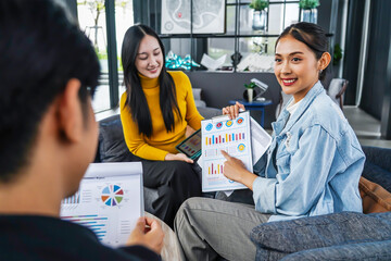 In a modern office, Asian businesswoman presents data summary charts on a tablet to her colleagues, financial report analysis teamwork strategy planning corporate success, marketing, data analytics
