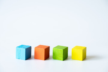 Obraz premium Four Colorful Wooden Cubes Arranged in a Row on White Background