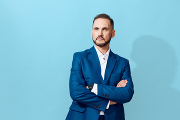A composed businessman stands against a solid light blue backdrop, exuding confidence and focus. He wears a tailored blue suit, arms crossed, projecting professional strength.