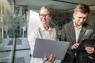 Collaborative teamwork in a modern office with two professionals using laptops