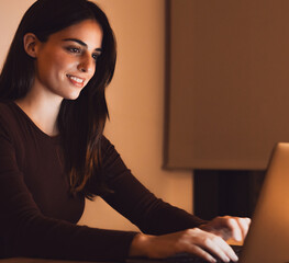 Head shot pleasant happy young woman freelancer working on computer at night. Attractive businesswoman studying online, using laptop software, web surfing information or shopping in internet store.