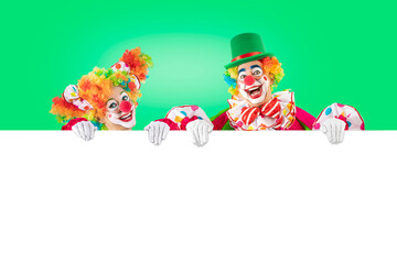 Funny clowns peeking out from behind sign blank template mock up for advertising, posters, greetings, invitations. Entertainers as Joker in a suit and wig, with clown whiteface makeup.