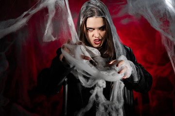 gothic woman with creepy vampire makeup trapped in spider web. Fantasy scary girl on red halloween...