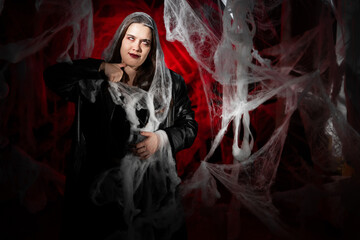 gothic woman with creepy vampire makeup trapped in spider web trying to scare. Fantasy scary girl...