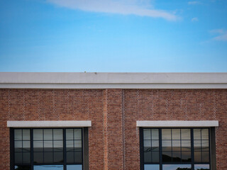 Minimalist View of Red Brick Wall and Industrial Windows Against Blue Sky