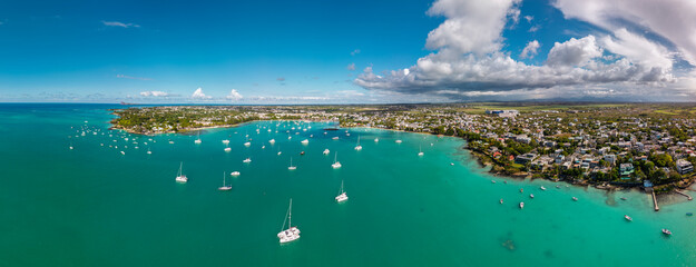 Aerial view of Grand Baie Mauritius with moored sailboats calm lagoon coastal neighborhoods and billowing afternoon clouds © ronedya