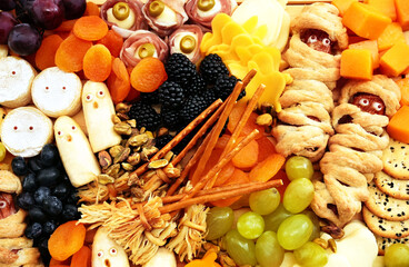 Healthy Halloween fun food mix: cheese ghosts and mummies, banana ghosts and grapes, blueberries and blackberries. Party spooky snacks for kids