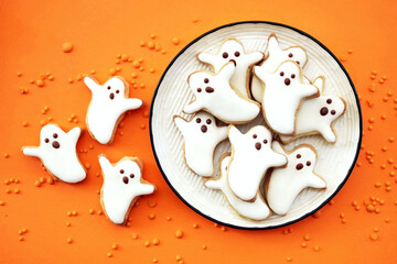 Healthy Halloween fun ghosts cookies on orange background. Party spooky sweet snacks for kids