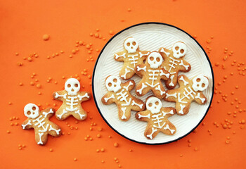 Healthy Halloween fun skeleton cookies on orange background. Party spooky sweet snacks for kids