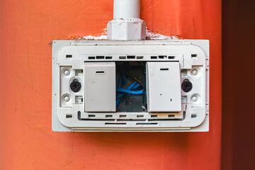 Dangerous broken electricity outlet socket and light switch on wall hole. Old damaged and broken electric switches and socket without cover on concrete wall. Power outlet sockets without the covering.