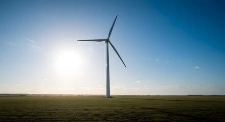 Sun Shining Behind a Wind Turbine in a Grassy Field Under a Clear Blue Sky