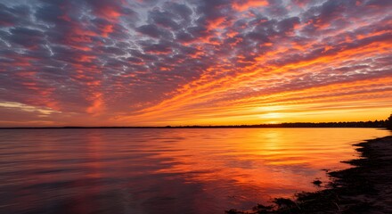 Vibrant Sunset Over a Calm Lake with Fiery Orange and Pink Clouds Reflected in Water