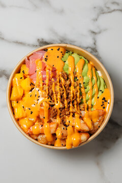 Shrimp poke bowl with avocado and sauce on marble background
