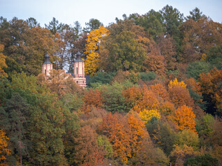 Calvary Church in Bardejov, Slovakia, partly hidden in autumn forest with colorful trees.